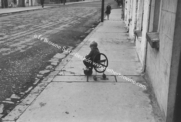 CHILD ON TRICYCLE IN STREET